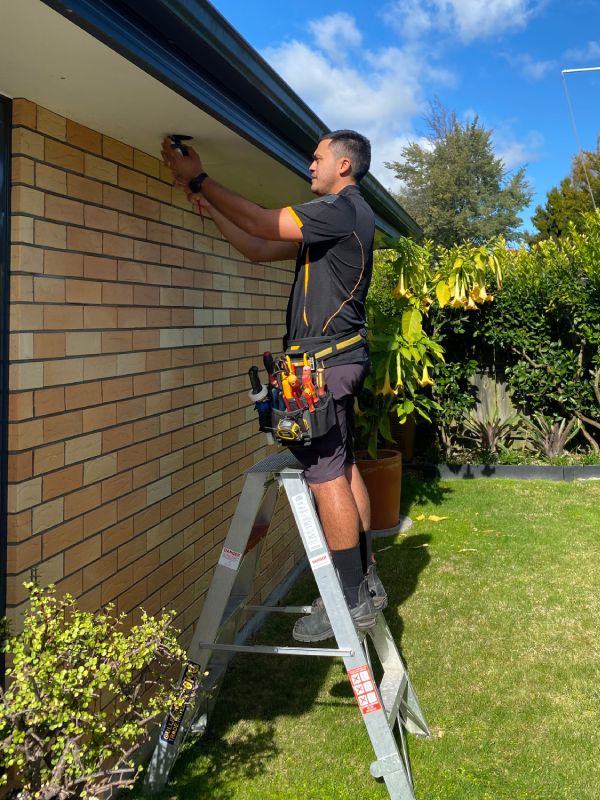 Stanley Ulrich fixing an outside ceiling light at a house.