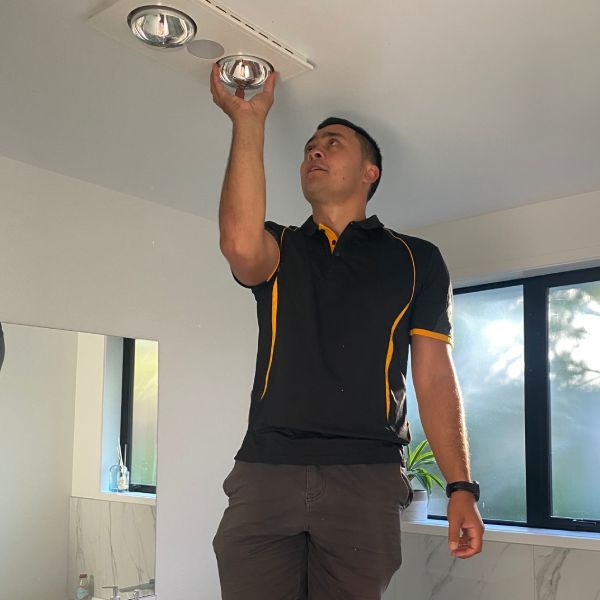 Stanley Ulrich replacing a light bulb in a ceiling of a residential house.