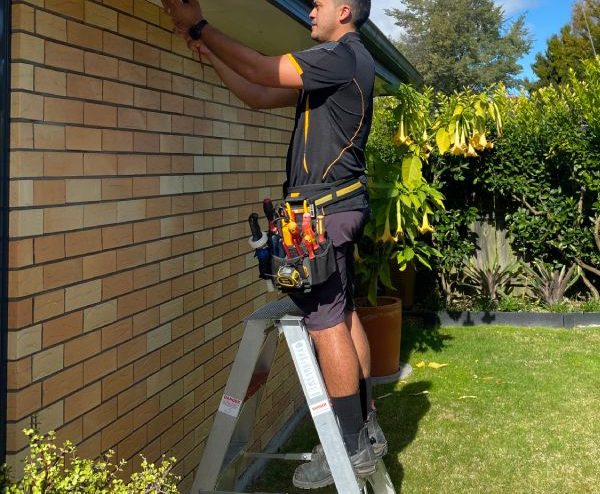 Stanley Ulrich fixing an outside ceiling light at a house.